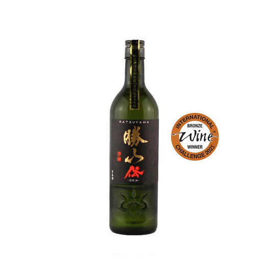 Front view of Katsuyama Junmai Daiginjo DEN sake bottle featuring a white textured label with bold black Japanese calligraphy and a red seal